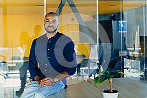 Happy african american businessman entrepreneur startup owner stand in modern office looking at camera, smiling young black