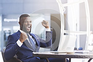 Happy African American Businessman Shaking Clenched Fists At Outdoor Cafe