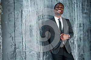 Happy african american businessman smiling and holding jacket while standing on wooden background