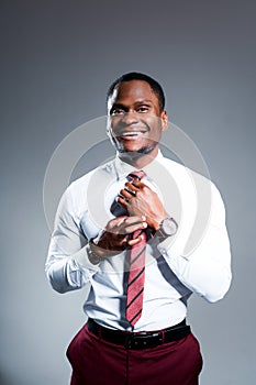 Happy african american businessman smiling and looking at camera while straightening tie