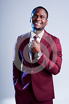 Happy african american businessman in suit smiling while standing on light background