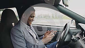 Happy african american businessman surfing social media on his tablet computer sitting inside his car