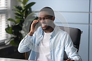 Happy african american businessman wearing glasses talking on phone.