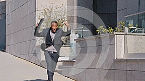Happy African American businessman winner leaving office building, excited by good news, got new job hired, receiving