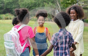 Happy African American childrens standing and holding hands together in circle in the park