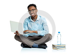 Happy african american college student with laptop, books and bo