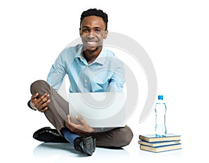 Happy african american college student with laptop, books sitting on white background