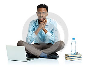 Happy african american college student with laptop, books sitting on white background