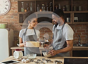 Happy african-american couple cooking cookies together