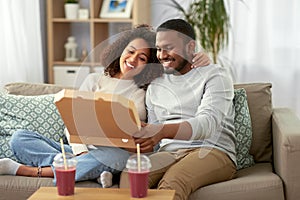 Happy african american couple eating pizza at home
