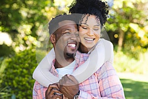 Happy african american couple embracing in sunny garden, copy space