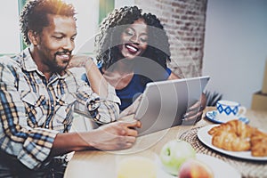 Happy african american couple are having breakfast together in the morning at the wooden table.Smiling black man and his