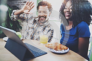 Happy african american couple are having video conversation together via touch tablet in the morning at the wooden table