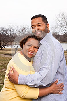 Happy African American couple hugging outside.