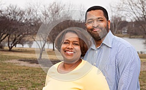 Happy African American couple hugging outside.