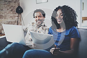 Happy african american couple relaxing together on the sofa.Young black man and his girlfriend using laptop at home in