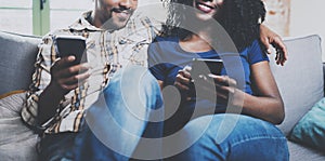 Happy african american couple relaxing together on the sofa.Young black man and his girlfriend using smartphones while