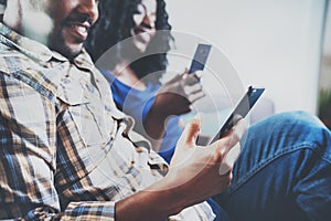 Happy african american couple relaxing together on the sofa.Young black man and his girlfriend using smartphones while