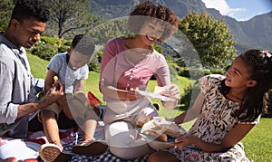 Happy african american couple with son and daughter outdoors, having picnic in sunny garden