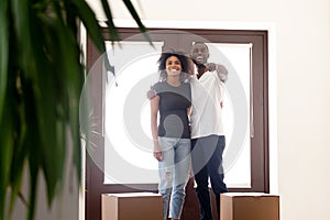 Happy African American couple standing in hall of new house