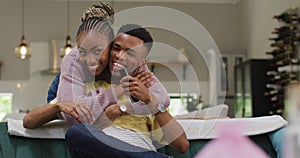 Happy african american couple talking and hugging on sofa