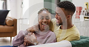 Happy african american couple talking and hugging on sofa