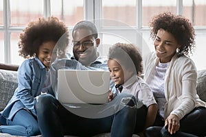 Happy African American couple and two kids relaxing on couch