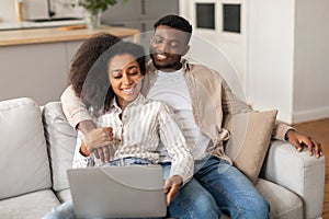 Happy African American couple using laptop pc watching video indoor