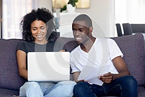 Happy African American couple using laptop, receive good news