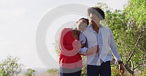 Happy african american couple walking together and holding hands on sunny day, slow motion