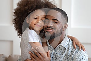 Happy african American dad and daughter cuddle touching cheeks photo