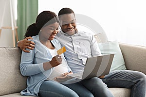 Happy african american expecting family using laptop, shopping online