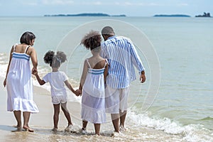 Happy African American family with African American father / asian mother and mixed race kids walking on the beach, thaliand