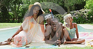 Happy african american family with beach equipment posing to photo at pool