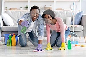 Happy african american family cleaning floor together in living room