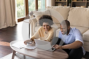 Happy african american family couple analyzing financial paper documents.