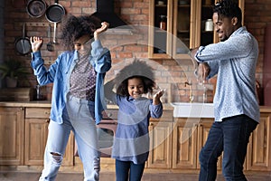 Happy African American family dancing in kitchen.