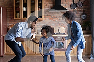 Happy African American family dancing in modern kitchen together