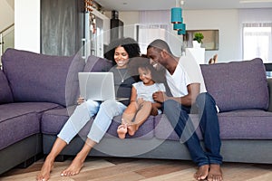 Happy African American family with daughter using laptop at home