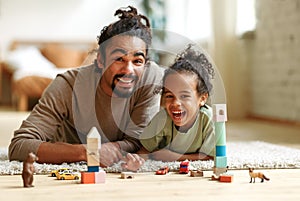 Happy african american family father and child son laughing while playing toys together at home