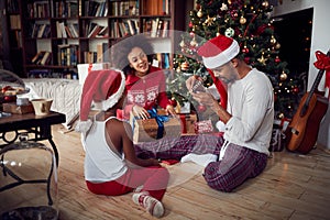 Happy African American family with girl and Christmas gifts on floor at home