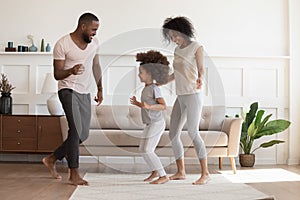 Happy african american family having fun, dancing at home.