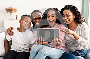 Happy african american family holding and using digital tablet computer