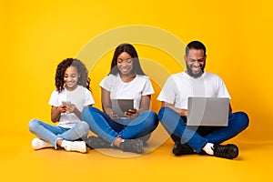 Happy african american family holding and using gadgets