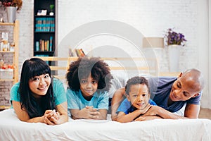 Happy African American family laying on bed at home, happily talking to each other. Parenthood and family concept.