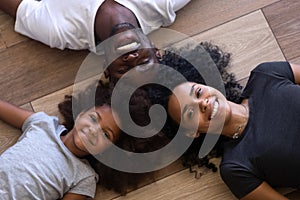 Happy african american family lying on floor looking at camera