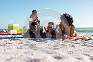 Happy african american family lying on towel while relaxing at beach on sunny day