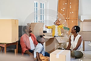 Happy african american family playing in new house with box filling material