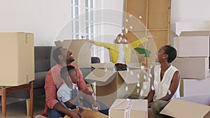 Happy african american family playing in new house with box filling material