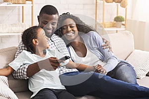 Happy african american family relaxing and watching TV at home